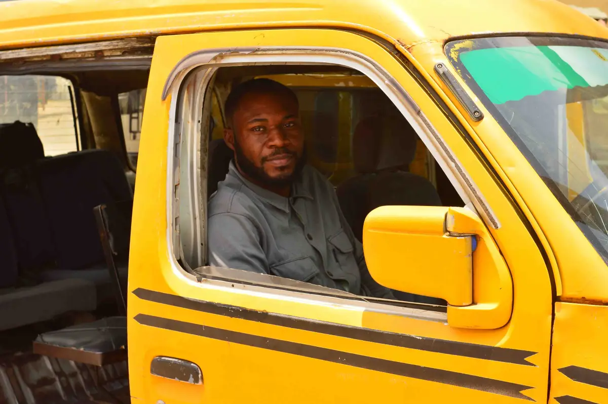 A danfo driver looks out from the window of his yellow bus.